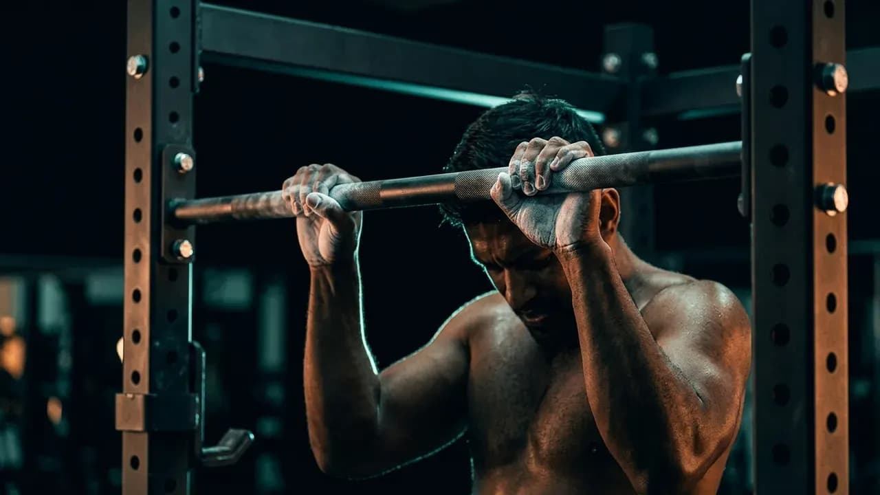 a chalk-covered lifter gripping a pull-up bar inside a power rack